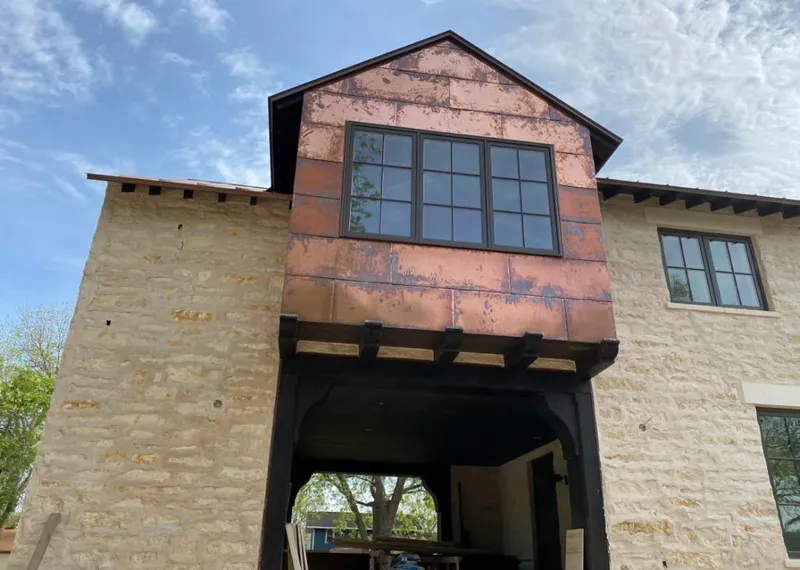 Copper metal panel facade on a stone building for Roof Repair in Tuttle